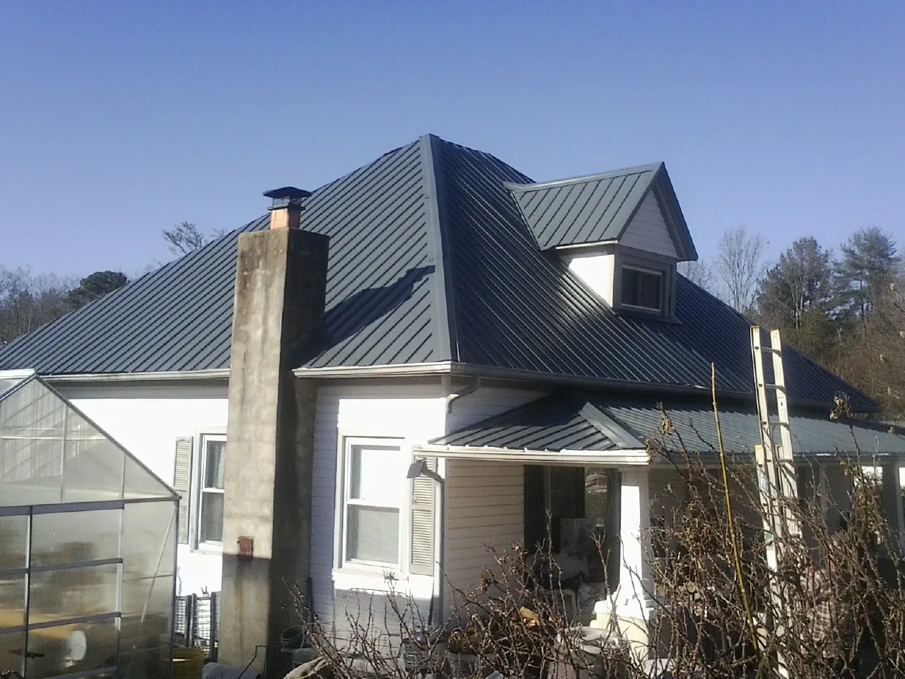 Dark blue standing seam metal roof on a white farmhouse with dormer — Slate & Tile Roof Repair by Roofing Brothers in Schoharie