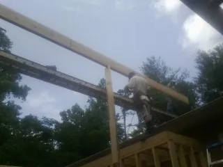 Carpenter setting a ridge beam over a new addition frame — Ice Dam Removal by Roofing Brothers in Schoharie