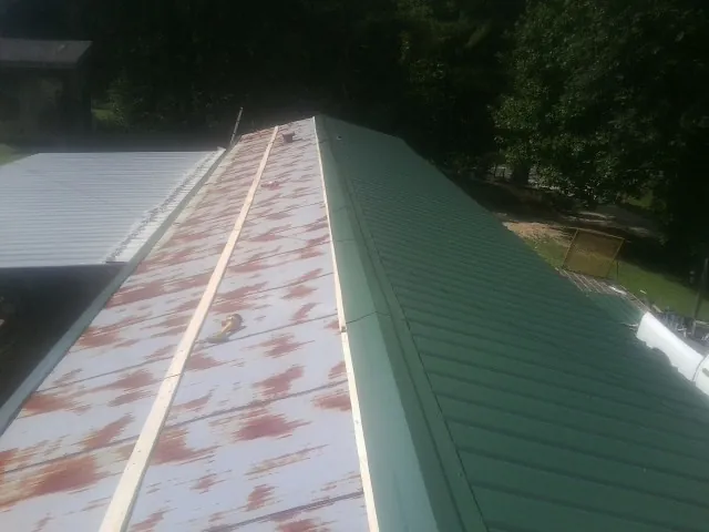 Old rusted panels beside newly installed green metal roofing — Wind Damage Roof Repair by Roofing Brothers in Schoharie