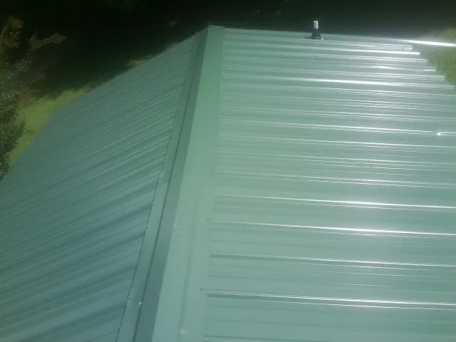 New green metal panels meeting at the ridge of a roof — Flat Roof Repair work by our crew in Schoharie