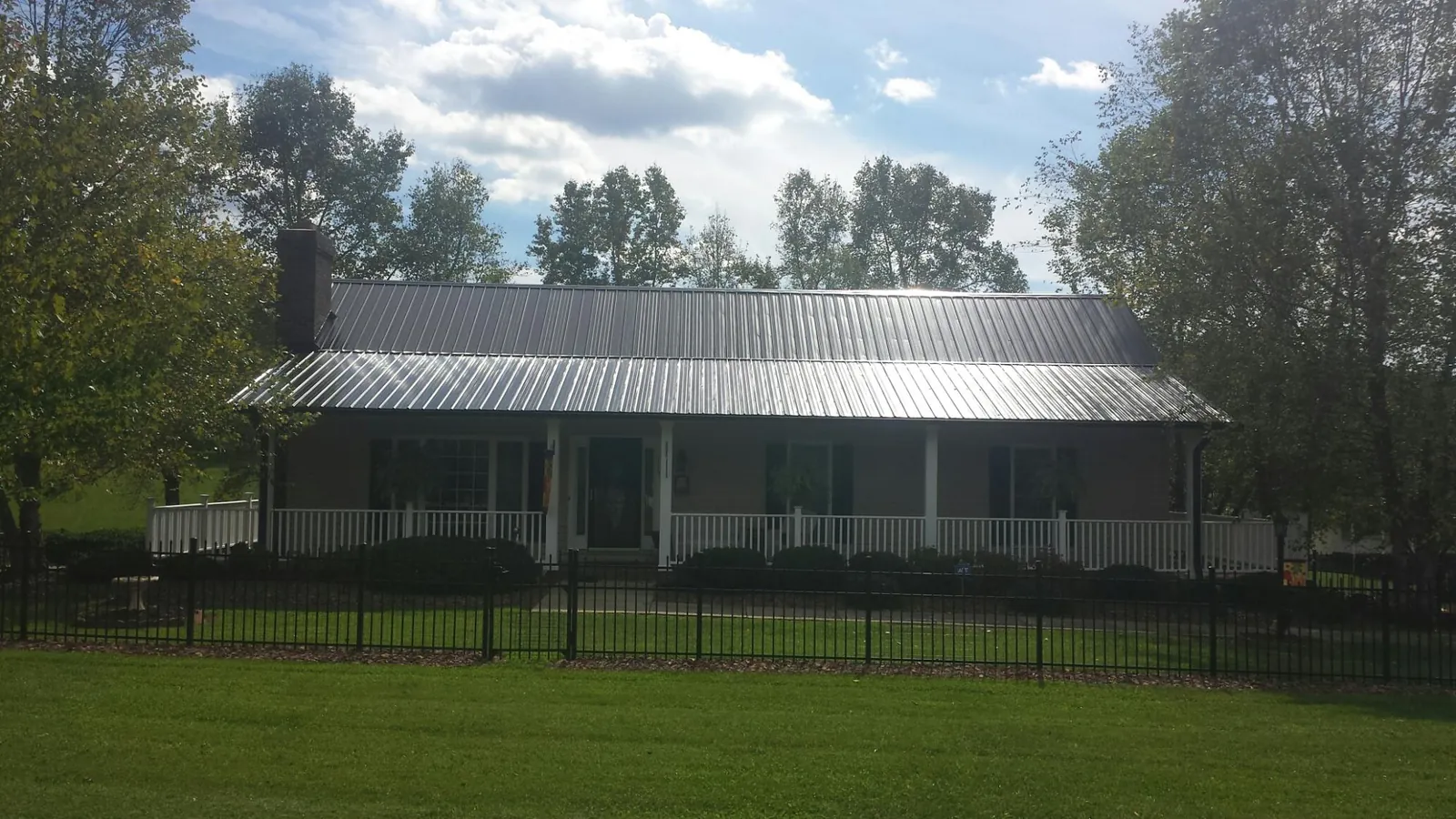 Gray metal roof on a brick ranch with a full width front porch — Gutter Guard Installation work by our crew in Schoharie