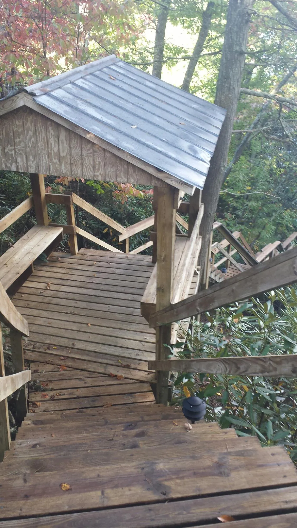 Metal roofed shelter over wooden steps on a wooded walkway — Skylight Repair & Installation work by our crew in Schoharie