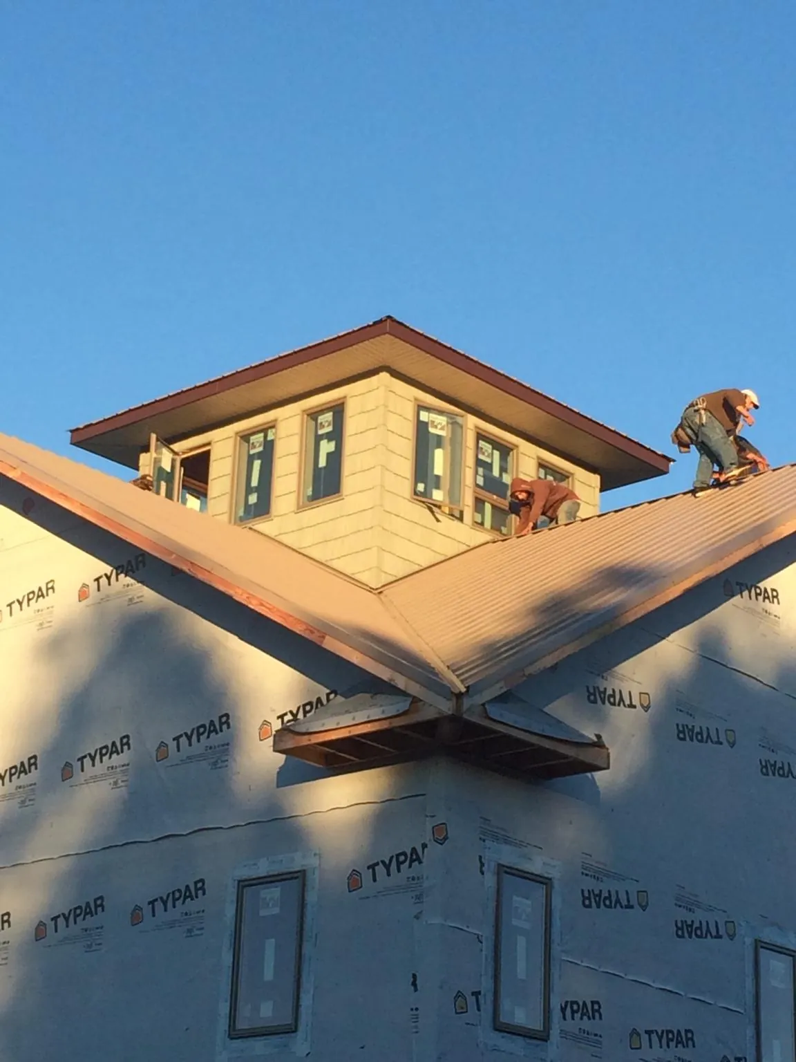 Roofers working around a rooftop cupola on a new metal roof at sunset — Roof Waterproofing in Schoharie by Roofing Brothers